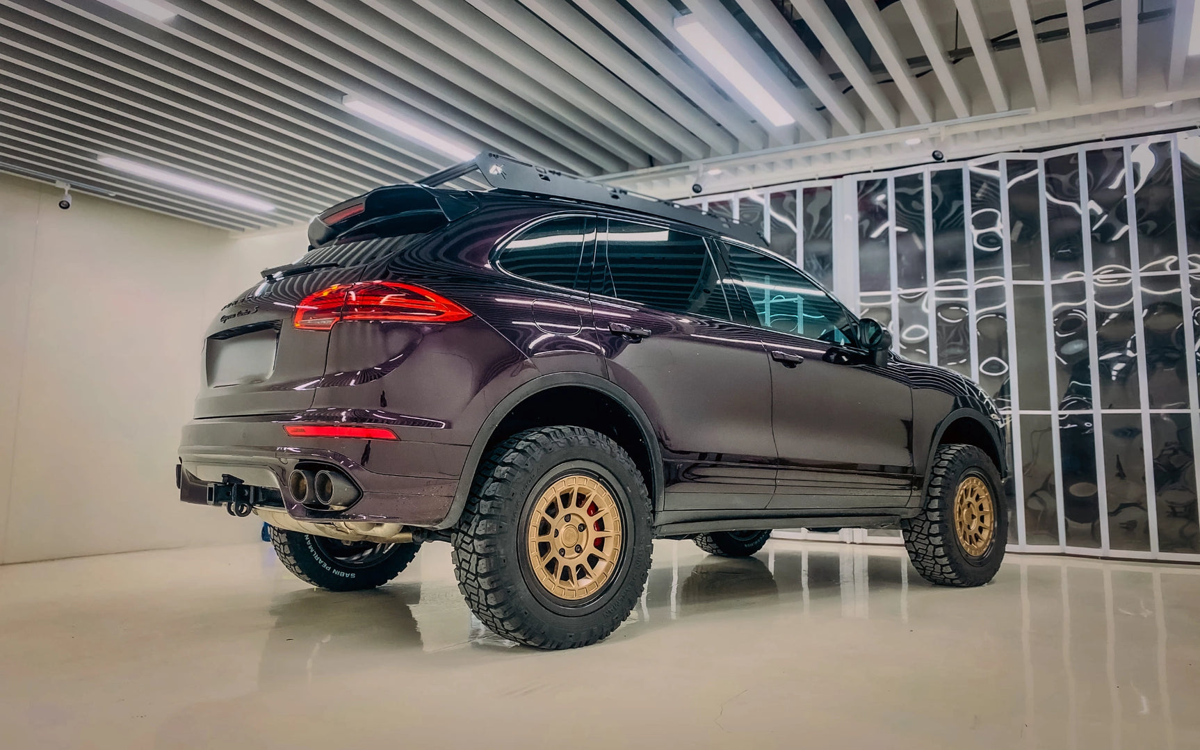 Porsche Cayenne turbo S with large off-road tires in a showroom setting