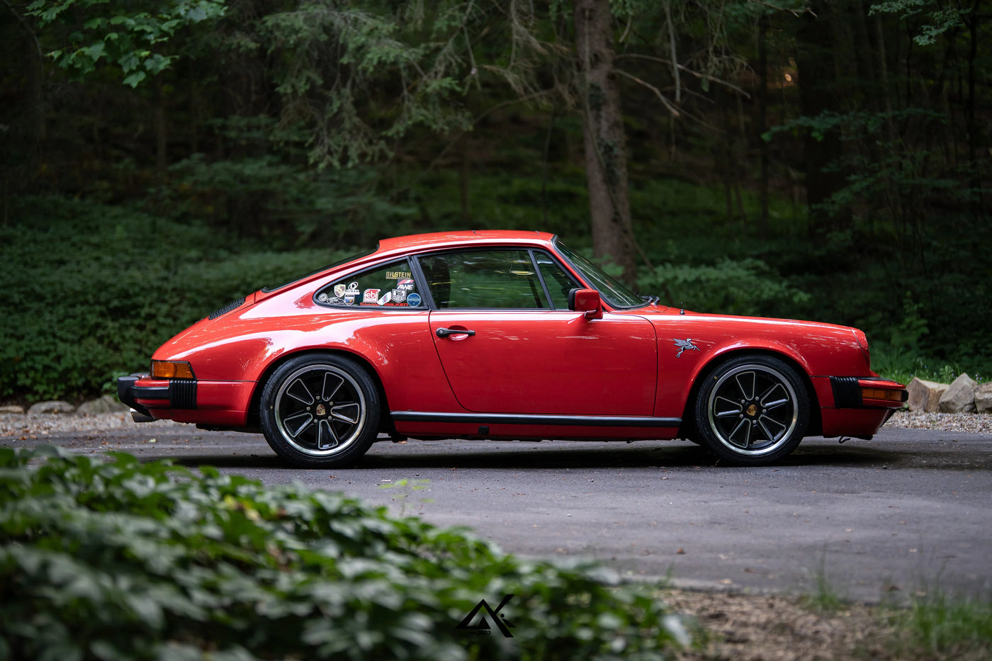 Red Porsche 911 SC G Body side profile with AkiOverland Fuchs Reimagined wheels on forest road