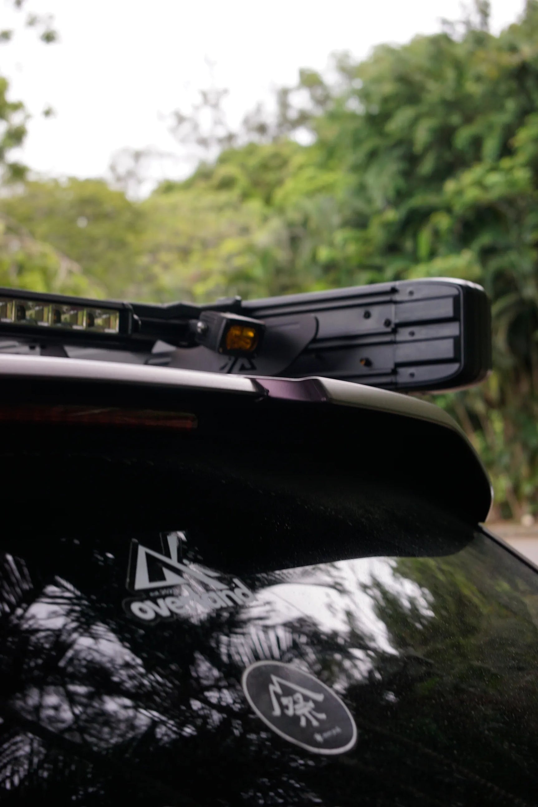 Gen 1 Porsche Cayenne roof rack with LED light bar on a vehicle with visible branding, set against a natural background.