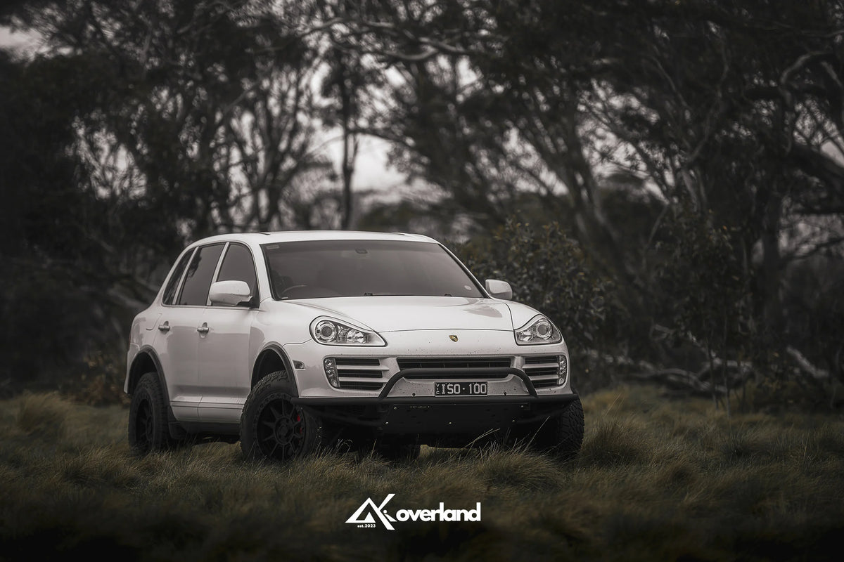 Porsche Cayenne 957 diesel off-road build by ISO100 featuring AkiOverland lift kit and steel tubular bumper, engineered by owners for owners
