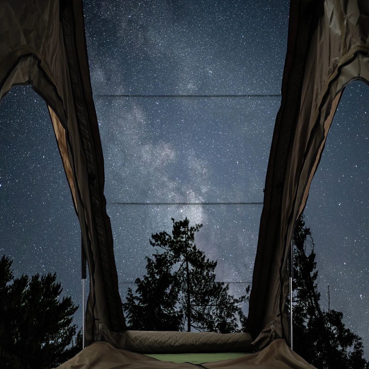Starry night sky view from inside a inspired overland tent with trees in the background