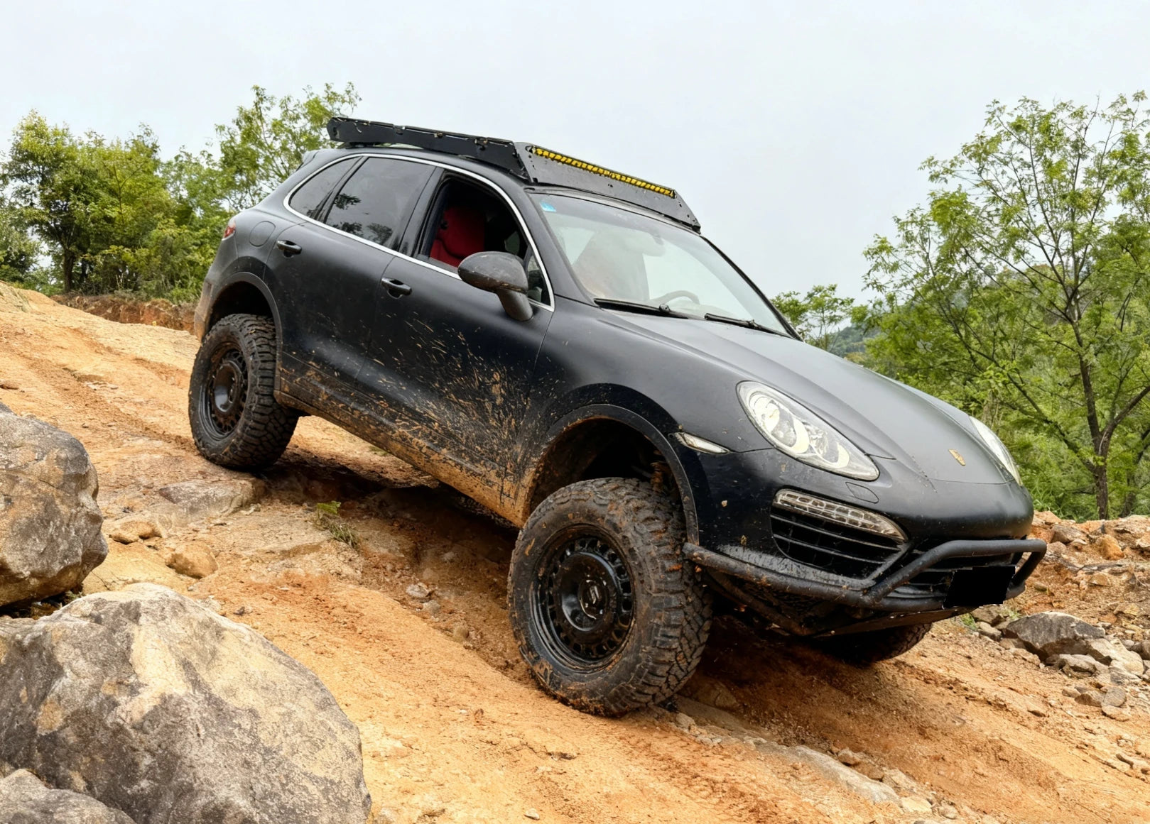 Lifted Cayenne 958 driving on rocky terrain with Akioverland UCA ensuring camber stability and axle clearance.