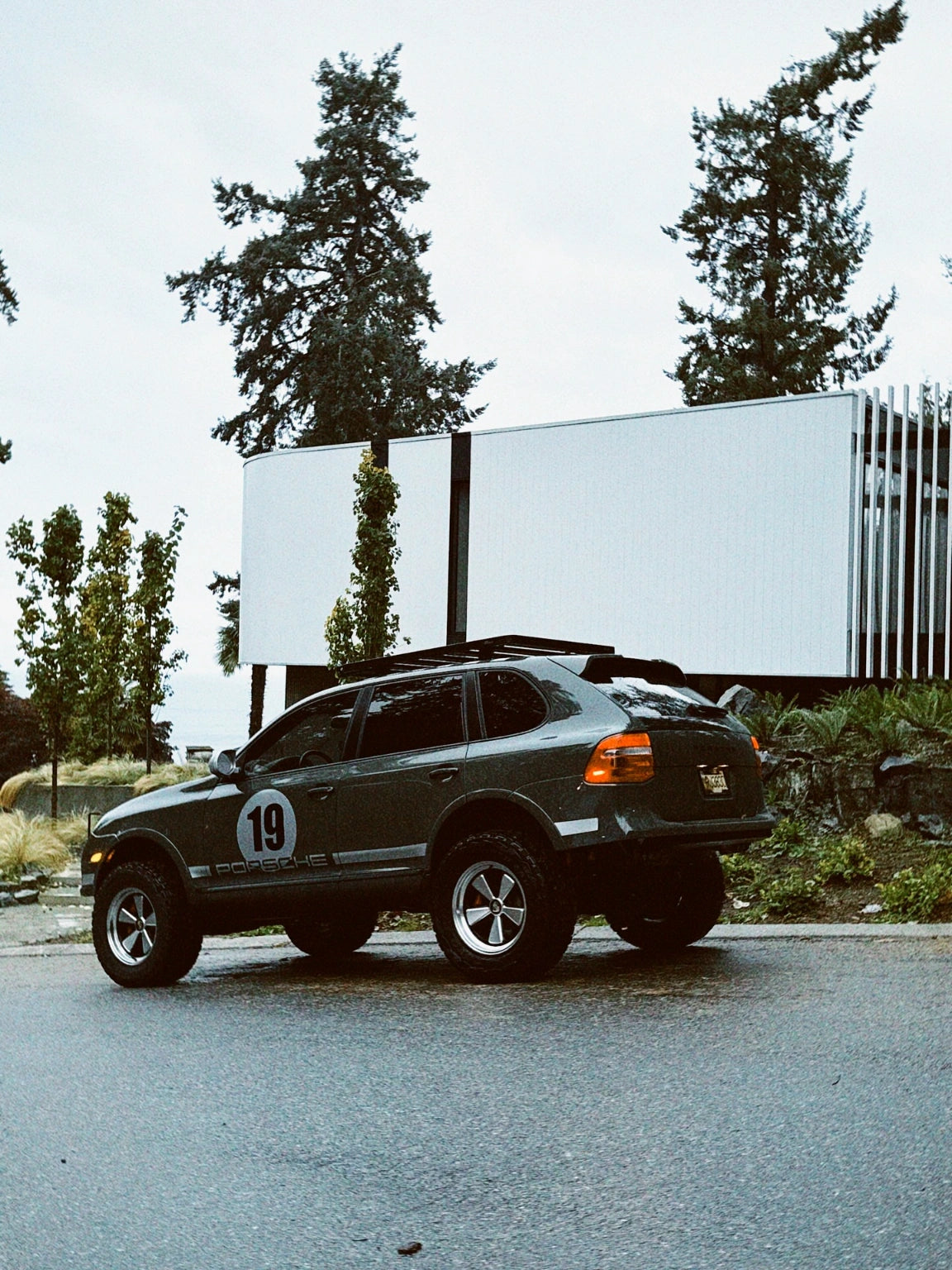 Cayenne 957 off-road build parked near modern building showing Akioverland lift kit and wheels
