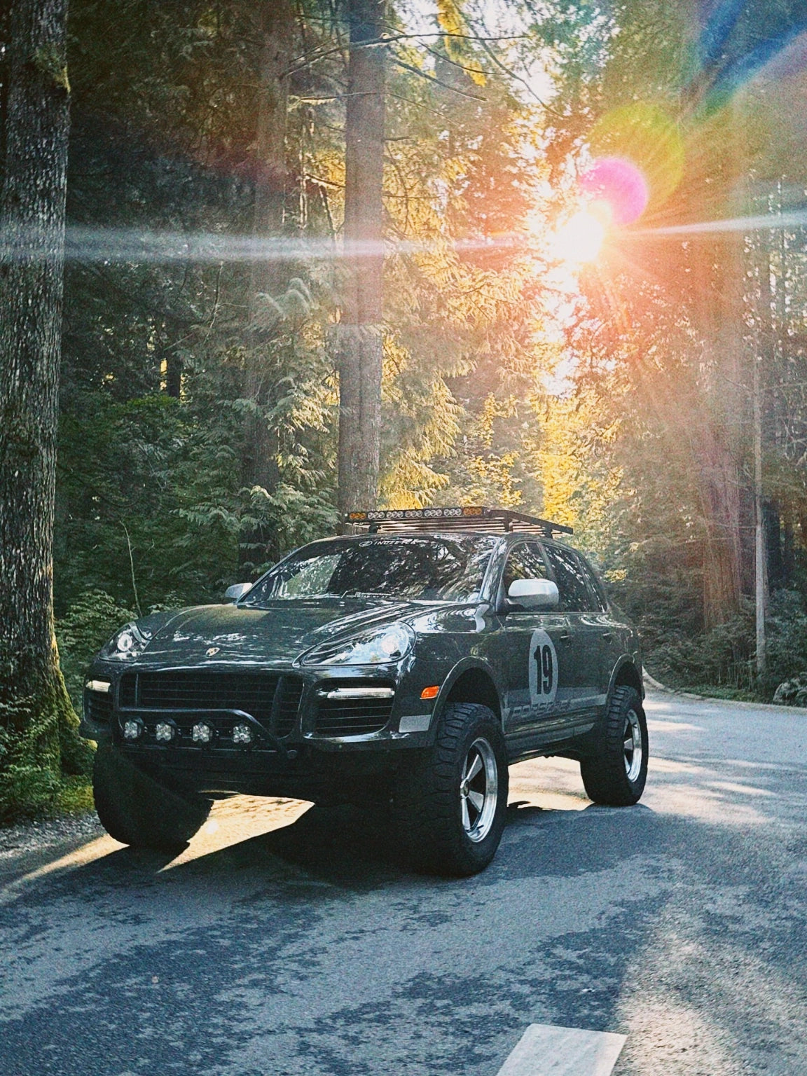 Lifted Porsche Cayenne 957 on AkiOverland Edition W forged 5x130 wheels on a forest road at golden hour sunset