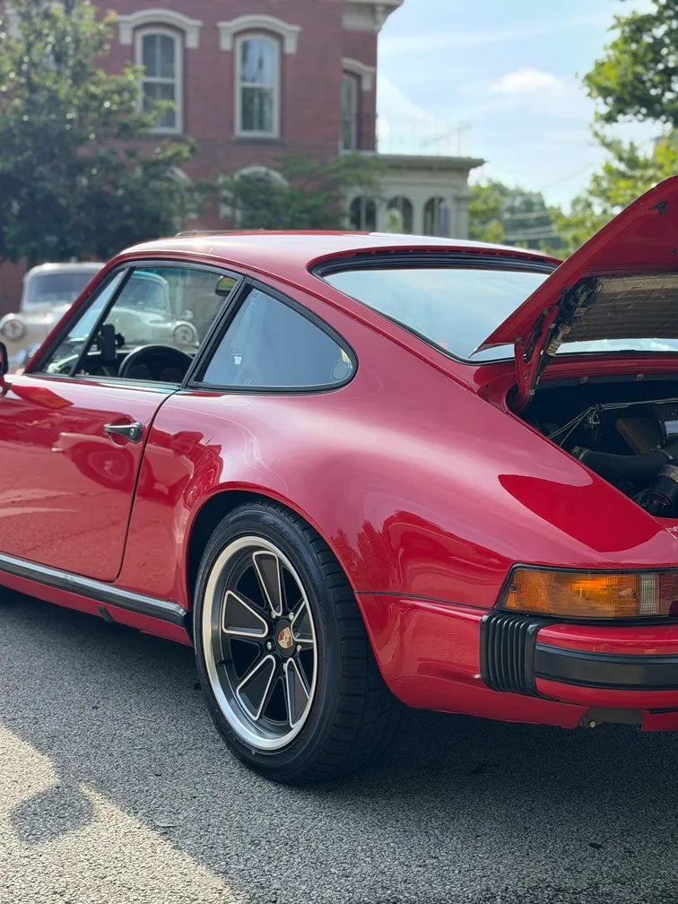 Rear view of 1982 Porsche 911 SC with engine lid open showing AkiOverland Fuchs Reimagined 5x130 wheel fitment