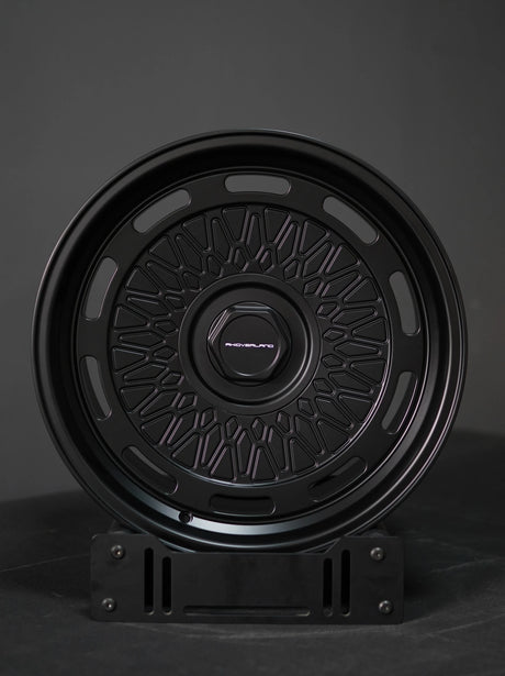 AkiOverland 5x130 mesh wheels in matte black shown front angle on display stand – Porsche offroad compatible.