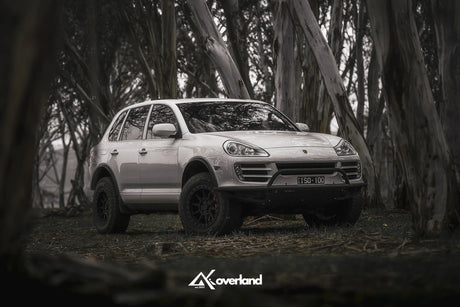 Porsche Cayenne 957 off-road stance with AkiOverland suspension lift, subframe drop and steel tubular bumper designed for winch installation.
