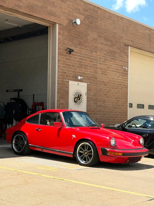 1982 Porsche 911 SC with AkiOverland Fuchs Reimagined wheels outside a Porsche specialist workshop