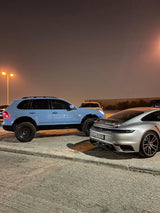 Rear view of a lifted Porsche Cayenne 957 Turbo on Akioverland's 3.5" air lift, alongside a Porsche 992 and 911