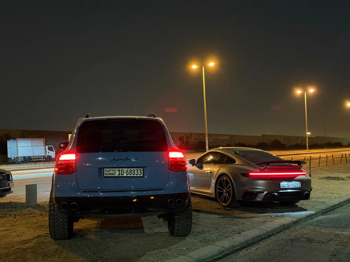 Rear view of a lifted Porsche Cayenne 957 Turbo on Akioverland's 3.5" air lift, alongside a Porsche 992