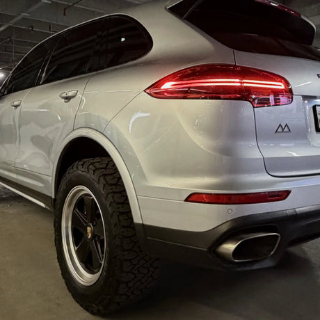 Lifted Porsche Cayenne 958 in silver photographed in a car park, running AkiOverland Classic Fuchs 2 Tone forged wheels