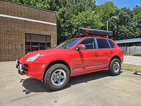 Classic red first-generation Porsche Cayenne 955 running AkiOverland Cookie Cutter Rugged forged wheels in machined and grey 2 Tone