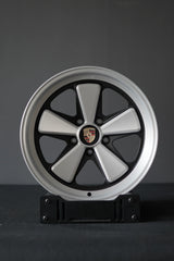 AkiOverland Edition W forged Fuchs-style wheel in 5x130 Porsche fitment, studio-mounted on a display stand