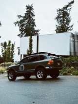 Cayenne 957 off-road build parked near  modern building showing Akioverland lift kit and wheels