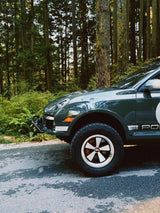 Porsche Cayenne 957 with 5x130 wheels and rally number 19 decal parked on forest trail