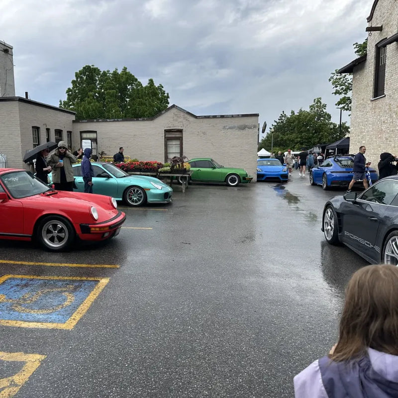 Porsche cars and coffee meet in Cleveland Ohio on a rainy day showing multiple air-cooled 911s, 718 Cayman GT4 and Macan Sully — community event where the AkiOverland x WrapWorkz Edition W build was discussed