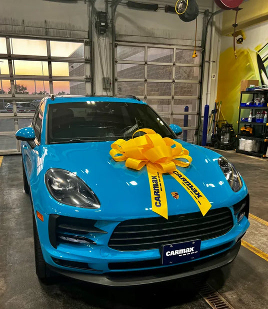2021 Porsche Macan Miami Blue Sully on purchase day at CarMax with yellow bow on hood — the beginning of the AkiOverland x WrapWorkz Edition W Forged Fuchs build story, Cleveland Ohio July 2025