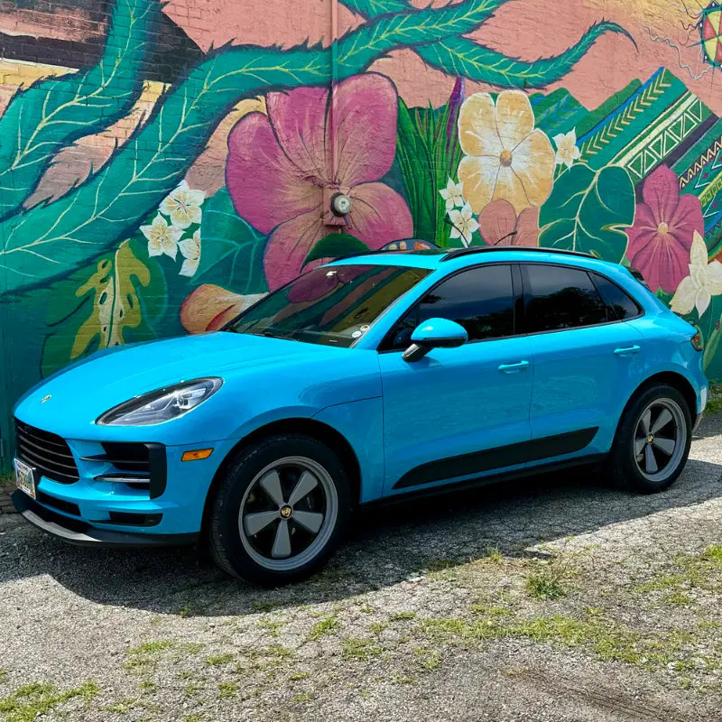 Full side profile of 2021 Porsche Macan Miami Blue Sully in sunshine against Ohio tropical floral street mural — pre-AkiOverland x WrapWorkz Edition W Forged Fuchs build