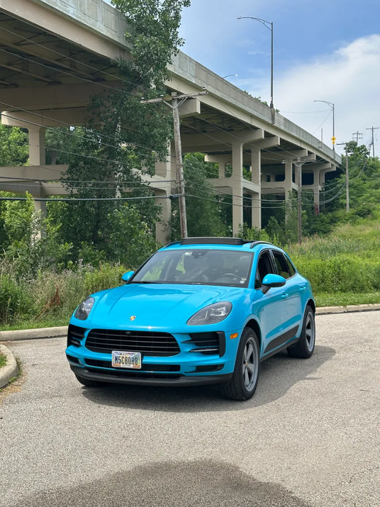 Straight front view of 2021 Porsche Macan Miami Blue Sully under Cleveland Ohio highway overpass — pre-AkiOverland x WrapWorkz Edition W Forged Fuchs wheel build, Cuyahoga area