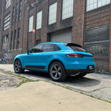 Rear three-quarter view of 2021 Porsche Macan Miami Blue Sully at Cleveland Ohio historic brick warehouse district with Terminal Tower in background — pre-AkiOverland x WrapWorkz Edition W build