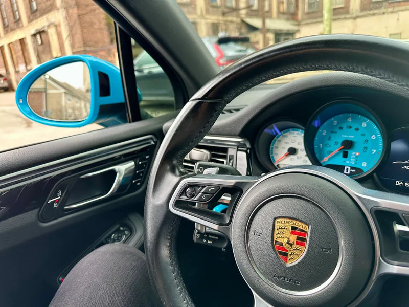 Driver perspective inside 2021 Porsche Macan Sully showing custom blue and white gauge face with Miami Blue door mirror visible — part of the AkiOverland x WrapWorkz Edition W build, Cleveland Ohio