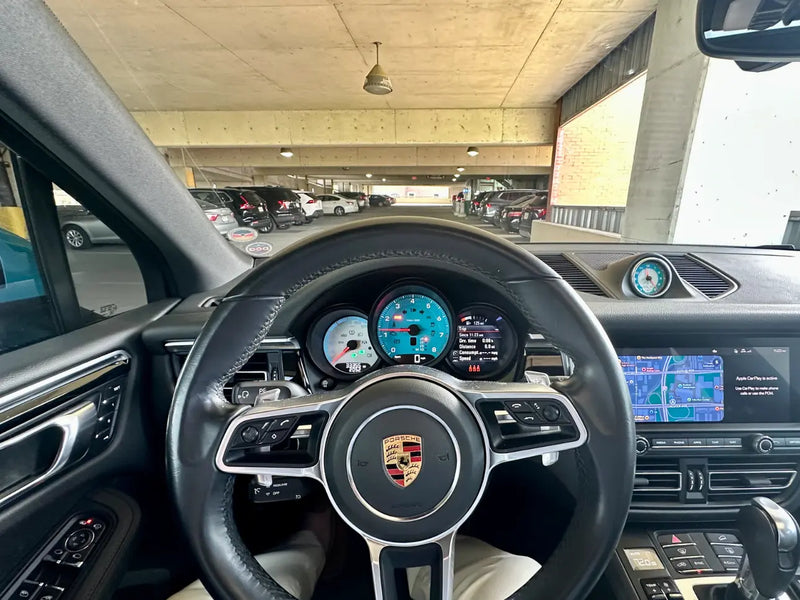 Driver point-of-view inside 2021 Porsche Macan Sully showing custom blue and white gauge cluster and Apple CarPlay PCM screen — AkiOverland x WrapWorkz Edition W build interior, Cleveland Ohio